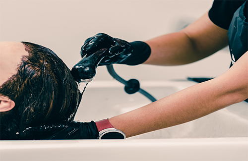 Beautiful brunette woman during hair wash in beauty salon