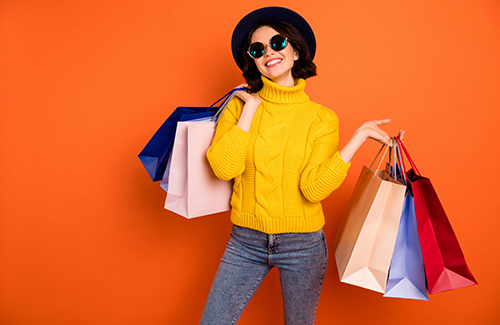 Photo of nice charming girl attractive joyful girl having just ended up shopping and being, overjoyed and cheerful while isolated with orange background